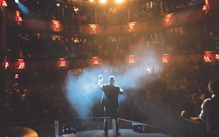 Luther sur scène lors d'un concert, éclairé par des projecteurs avec une foule en délire