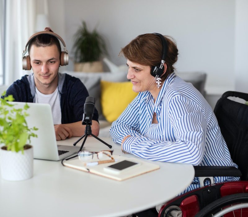 disabled-people-sitting-at-the-table-indoors-at-home-recording-podcast-at-home.jpg